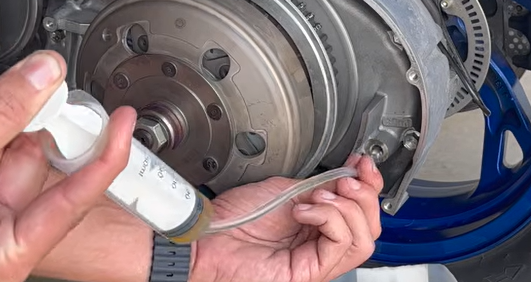 Refilling Suzuki Burgman 400 final drive gearbox oil using a 60ml calibrated syringe and clear hose
