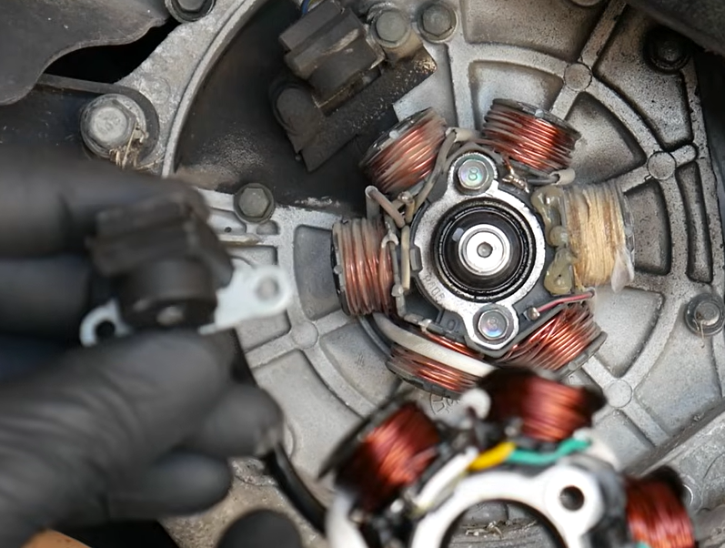 Close-up of a GY6 flywheel puller threaded into the flywheel hub