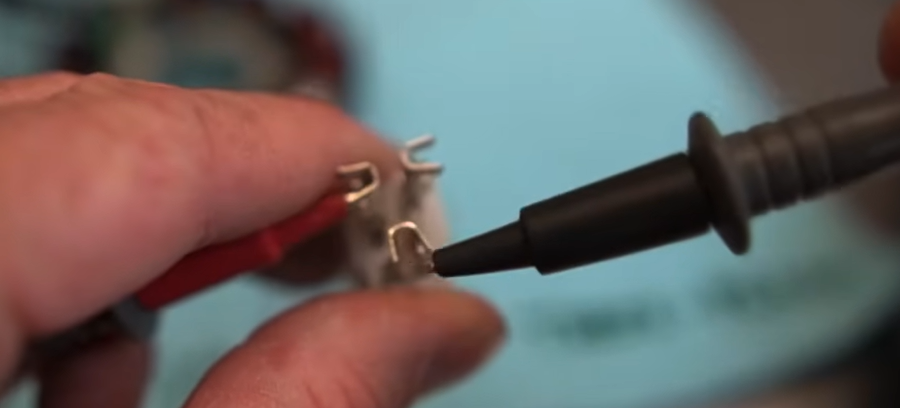 Digital multimeter probes testing the GY6 stator harness connector for resistance