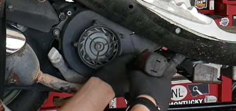 Technician removing the cooling fan shroud to expose the GY6 flywheel