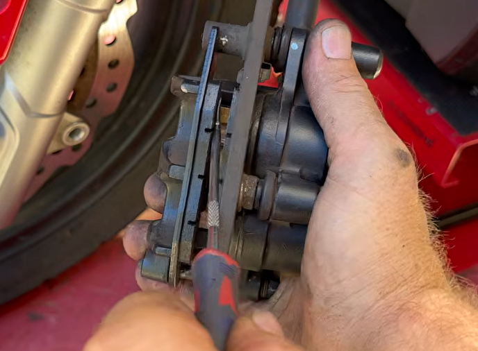 New OEM rear brake pads installed over the Honda ADV 150 rear brake disc rotor