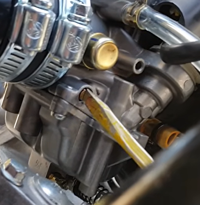 Screwdriver adjusting recessed GY6 idle mixture screw on Kymco carburetor side casting