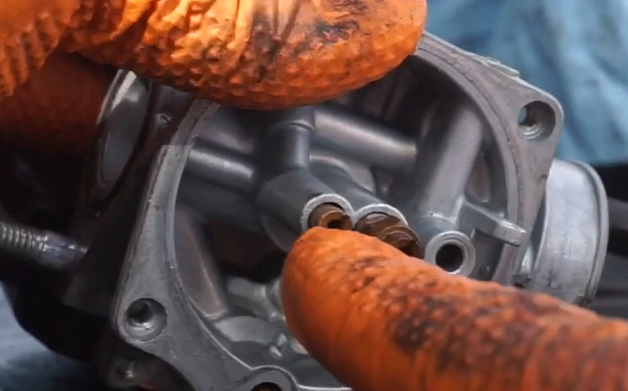 Float bowl removed from Kymco Agility carburetor showing ethanol varnish deposits