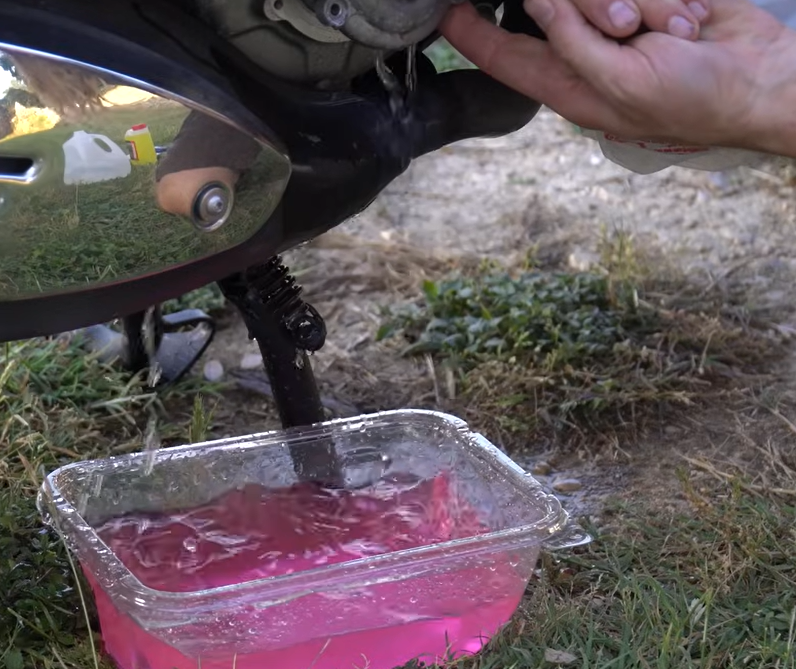 Pouring distilled water into the Vespa GTS expansion reservoir using a clean funnel