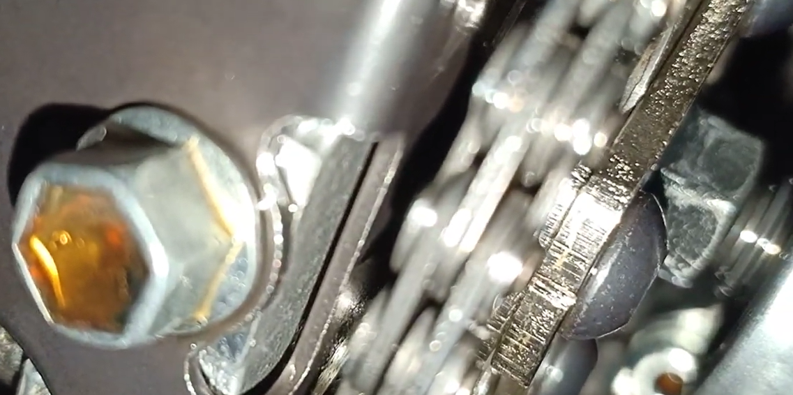 Feeler gauge blade inserted beneath the NMAX exhaust rocker arm to measure valve clearance