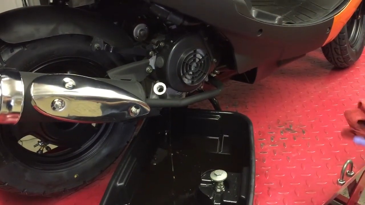 Oil dipstick and fill port removed, showing oil draining from main frame drain plug