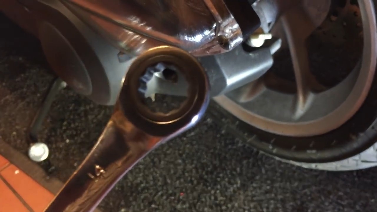 Left shock bottom bolt access showing the tight clearance between the airbox and suspension arm on the Yamaha NMAX